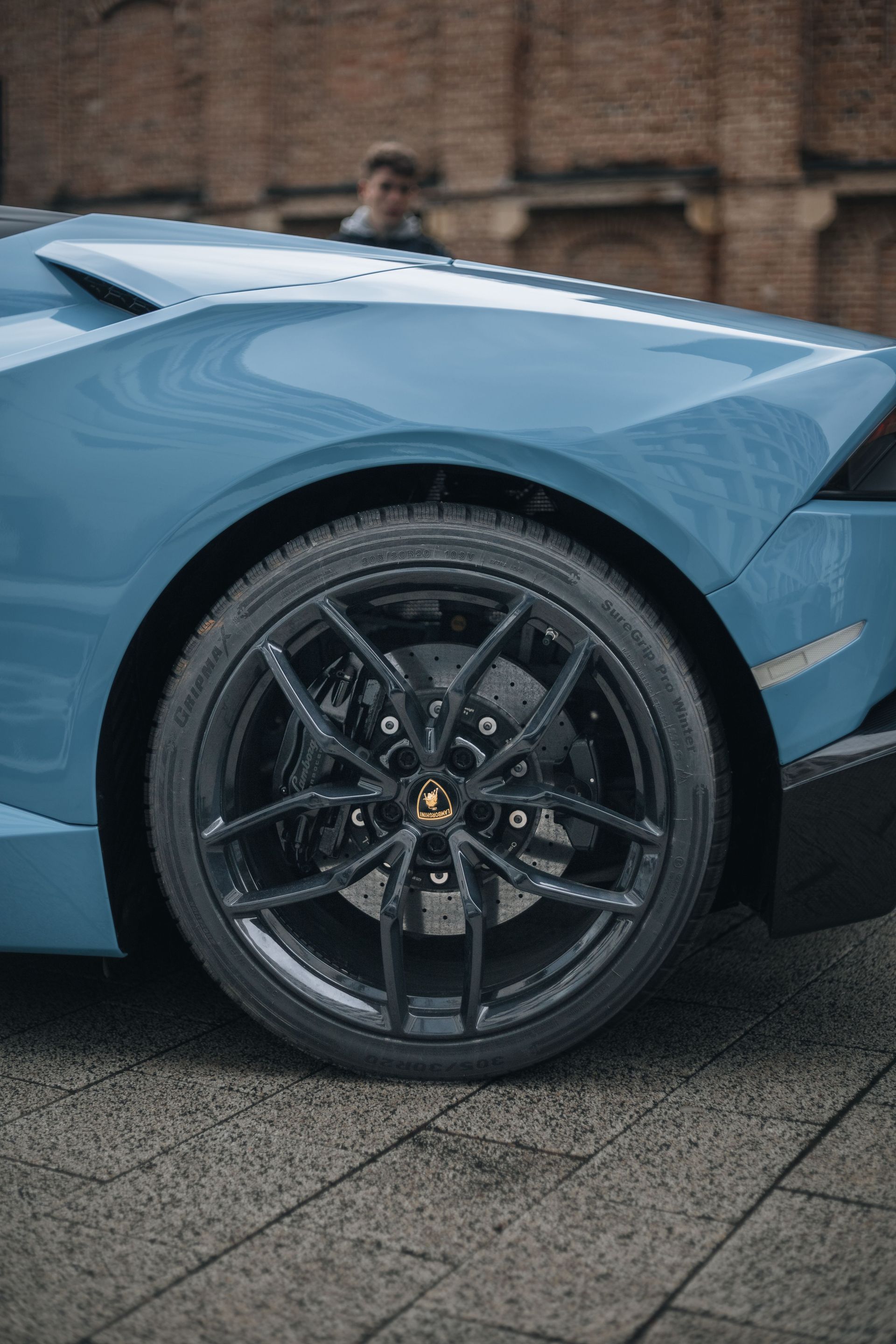 Detailed view of a luxury sports car wheel with a blurred background in Cluj-Napoca, Romania.