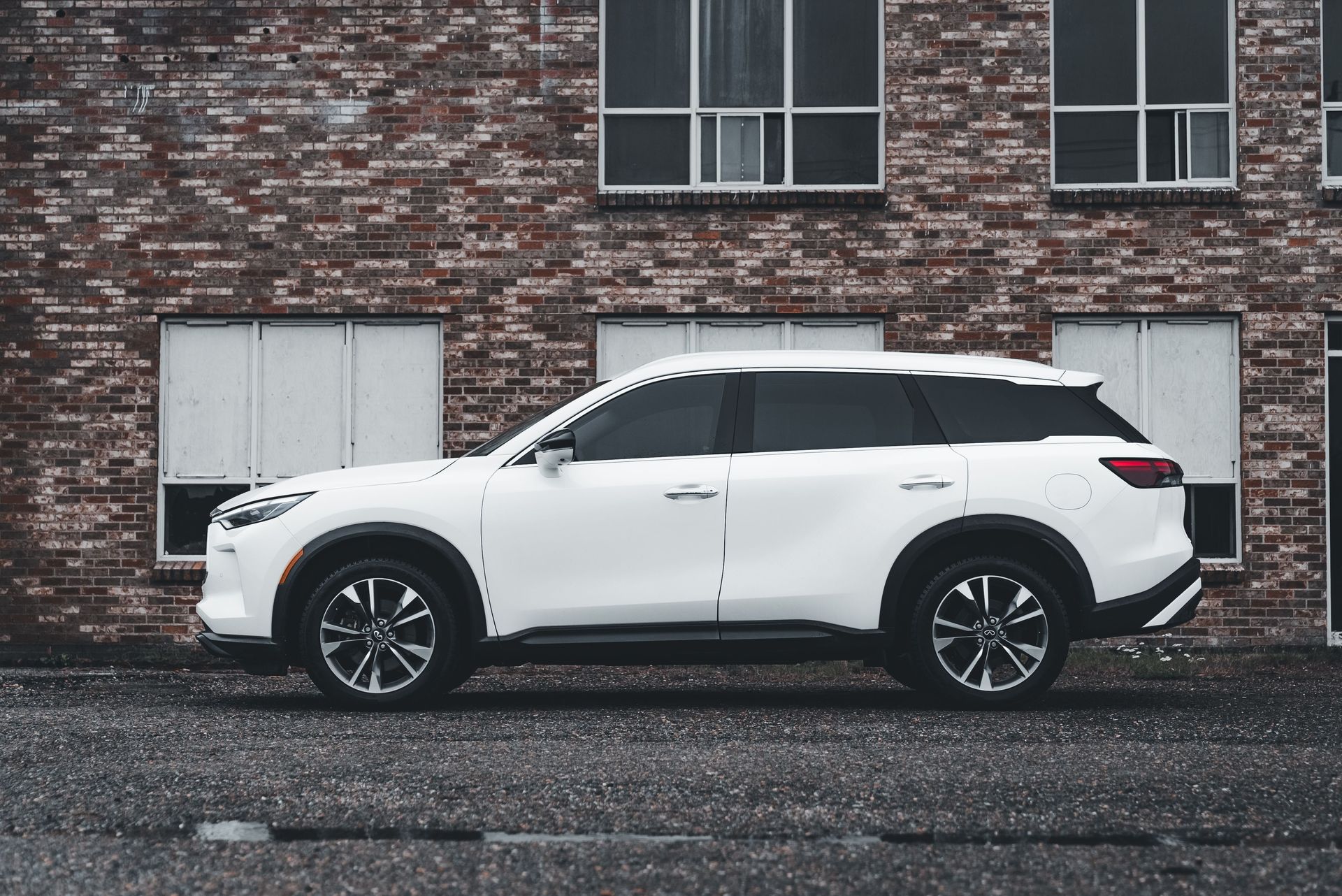 Modern white SUV parked against a rustic brick wall, showcasing style and elegance.