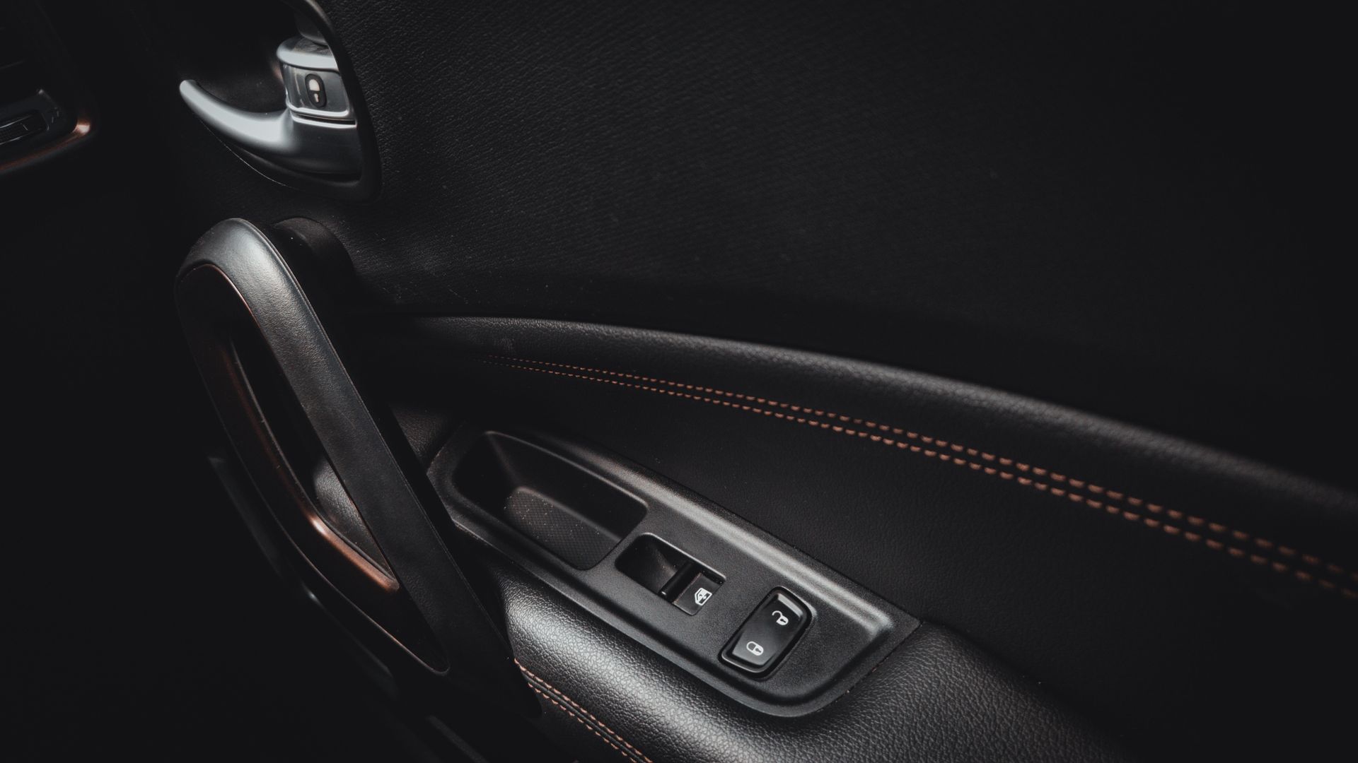 Detailed view of a car door interior showcasing handle and stitching.